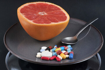 Pamplemousse avec un mélange de médicaments dans une assiette sur fond noir