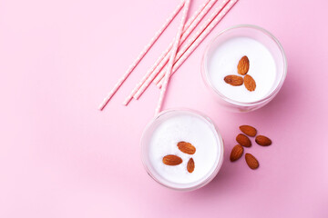 Two glasses with almond milk, pink tubes on a pink background. View from above