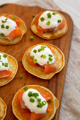 Homemade Blini with Smoked Salmon, Creme and Chives on a rustic wooden board, low angle view. Close-up.