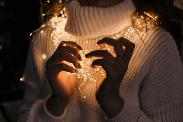 girl in a white sweater wrapped in a christmas garland