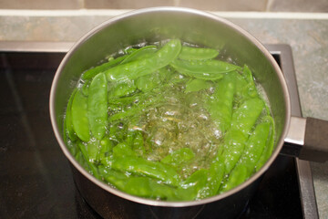 Mangetout cooking in a pan of water on an electric hob