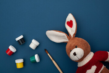 plush bunny on a blue background with paints and a brush