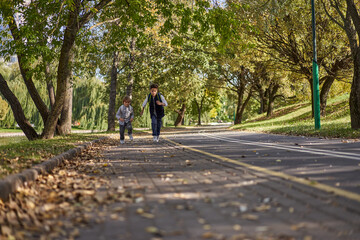 Happy woman riding on an e-scooter with her son. Young and beautiful caucasian woman rides electric scooter with boy in park.