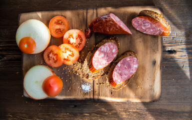 Sausage slices and sandwiches on a wooden Board,with slices of tomatoes,onions with slices of bread,still life
