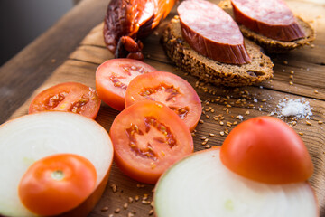 Sausage slices and sandwiches on a wooden Board,with slices of tomatoes,onions with slices of bread,still life