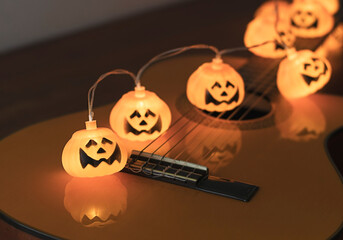 halloween pumpkin string lights glowing  on acoustic guitar. Halloween party concept.