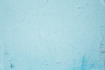 The texture of the old wall with cracked peeling blue paint. Background.