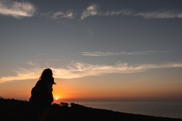 Naklejka na ściany i meble Silhouette of a woman on a sunset background