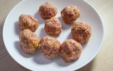 Raw beef meatball on a white plate.