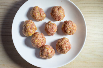 Raw beef meatball on a white plate.