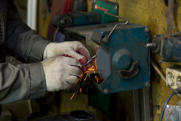 Locksmith's hands in white protective gloves with a drill