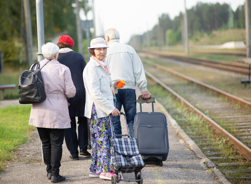group of seniors elderly old people with luggage waiting for a train to travel