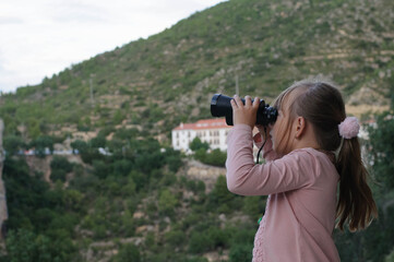 girl with binoculars on the background of the mountain