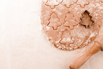 Christmas baking background with copy space for a greeting text, peace of dough rolled out for cooking Xmas gingerbreads, top down view