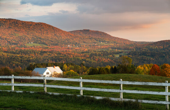 home tucked away in a valley next to a white old fence in the hills during the late afternoon light glowing golden during fall colors 