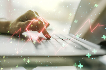 Double exposure of creative abstract heart rate hologram and hands typing on laptop on background. Healthcare technolody concept