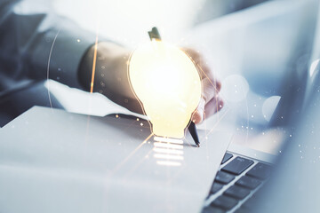 Creative light bulb illustration with hand writing in notepad on background with laptop, future...