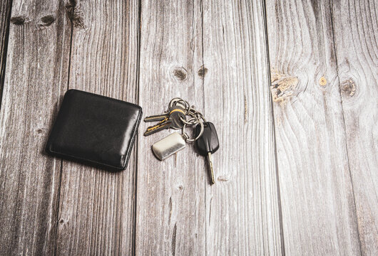 A wallet and a set of keys laid on a rustic wooden table or desk