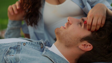 Obraz na płótnie Canvas Brunette girl stroking guy hair outdoors. Man and woman lying on the ground