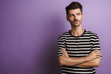 Photo of young serious man posing with arms crossed on camera