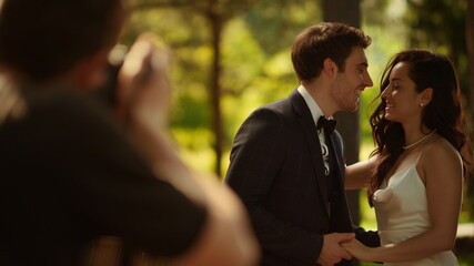 Happy couple posing on photo session. Bride and groom showing rings outdoors