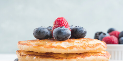 Stack of pancakes with fresh blueberries served in a dish with maple syrup. Delicious breakfast closeup banner