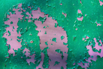 The texture of peeling green paint from pink, as a background, concept. View from above
