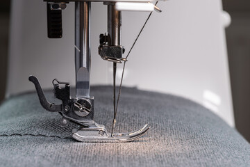 A sewing machine needle with thread. Sewing equipment. Close-up of the working area of the sewing...