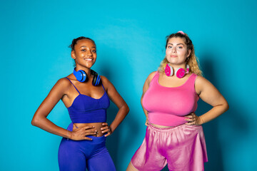 Fit and oversize young adull posing on blue background - Diverse women with different body shapes...
