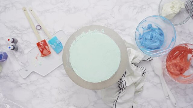 Step by step. Piping buttercream rosettes on top of round three-layer vanilla cake.