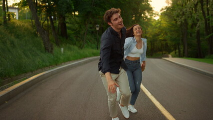 Happy man and woman having fun outdoors. Happy couple running on road in park