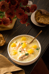 Chicken, rice and pumpkin soup in a plate with a spoon, delicious lunch or breakfast, flowers in a...