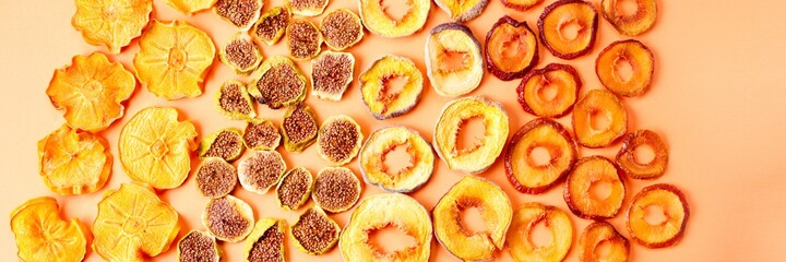 slices of dried persimmon, peach, plum and figs on a orange background. dried fruits. eco.