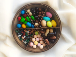 colorful almond dragee and filled chocolate in a brown candy bowl