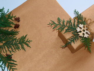 New year gift in brown paper and branches of pine and thuja, copy space, place for text