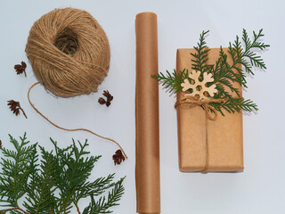 Gift wrapping, white background gift wrapped in craft paper, wrapping paper, twine and thuja. Gift for Christmas or New Year