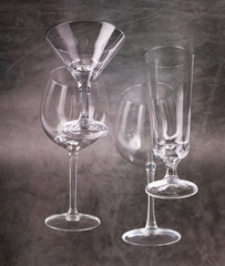 Glass wine glasses of various shapes and sizes on a gray background.