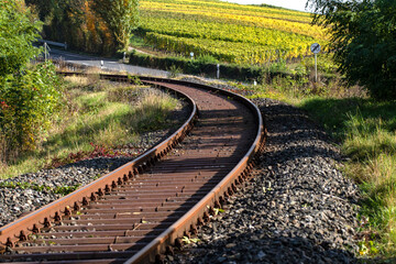 Eisenbahnschienen der Mainschleifenbahn von Volkach nach Seligenstadt in Mainfranken im Hintergrund herbstliche Weinberge
