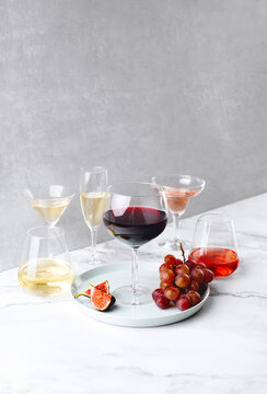 Various types of wine in different sort of glassware standing on a marble table surface