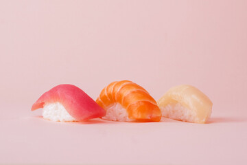 Salmon, tuna and perch sushi set on pink background