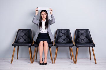 Portrait of her she nice attractive scared lady executive company manager sitting in chair holding document over head like roof insurance wait meeting isolated pastel gray color background