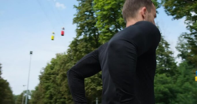 Man in sportswear doing triceps dip exercise on parallel bars at park