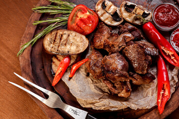 Lamb roasted over charcoal with sauce and spices on a wooden board.