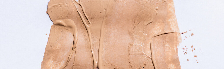 top view of beige face foundation brushstrokes on white background, panoramic shot