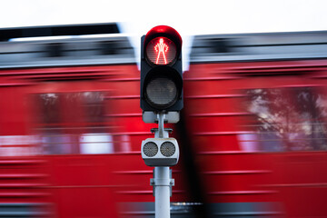 red traffic light. the train passes in the background a blur in motion