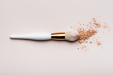 top view of cosmetic brush with face powder on beige background