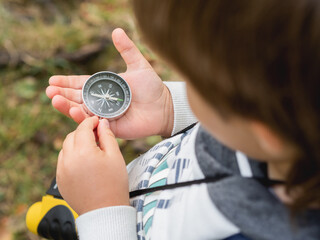 Little explorer on hike in forest. Boy with binoculars and compass sits on stump and reads map. Outdoor leisure activity for children. Summer journey for young tourist. © Konstantin Aksenov