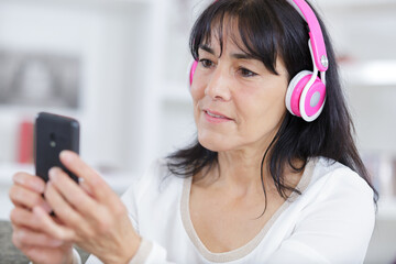 portrait of mature woman using smartphone and headphones