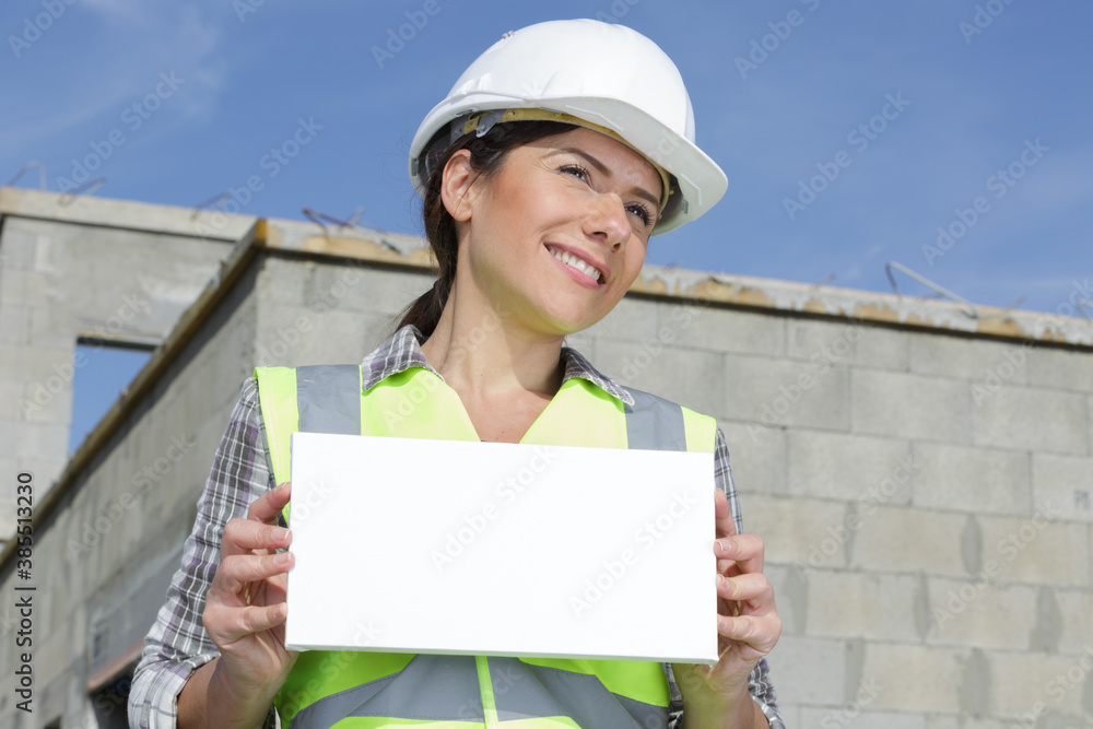 Wall mural female builder outdoors holding blank sign