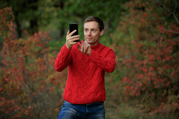 Man in red sweater make a photo by smartphone